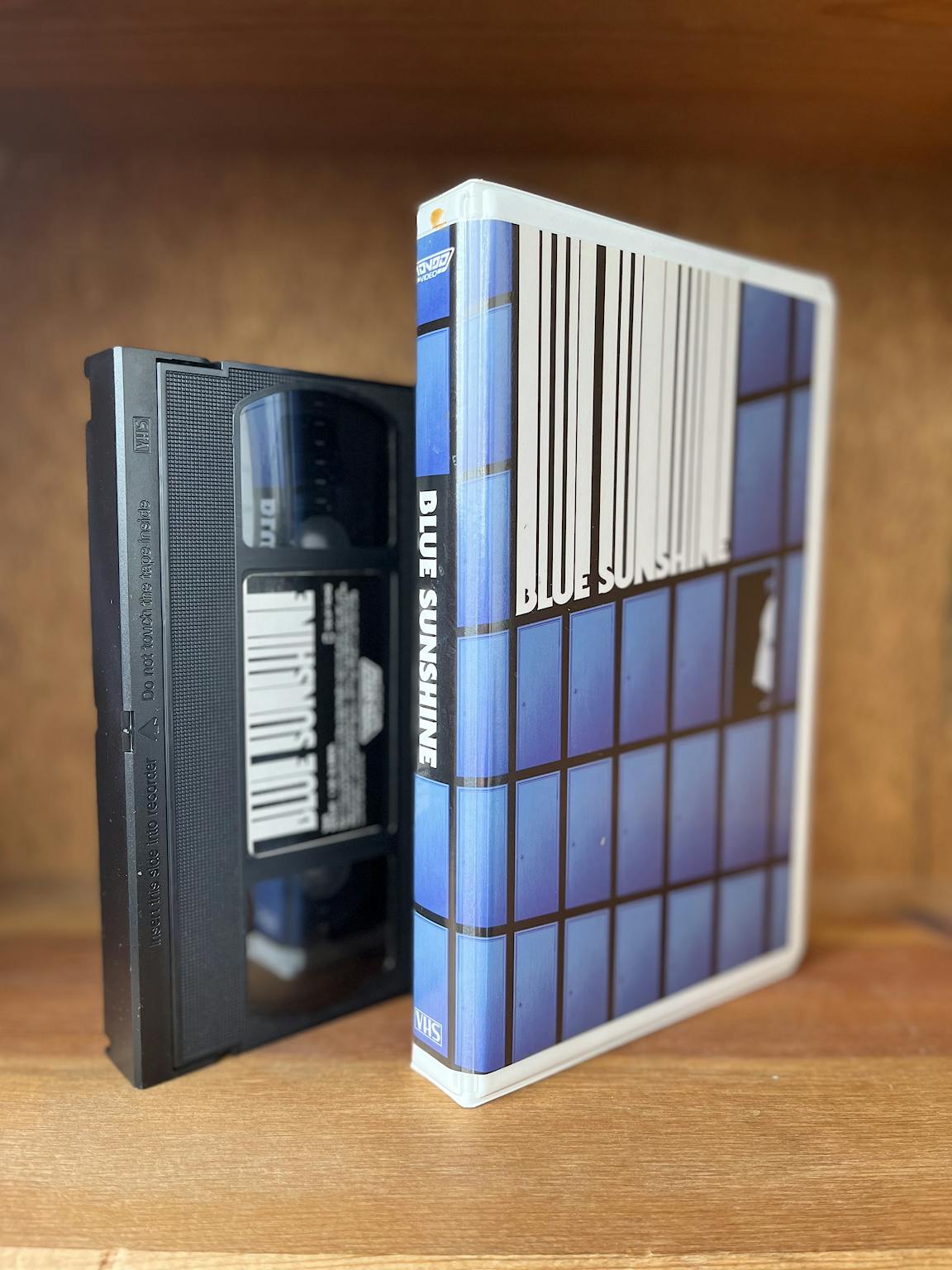 A blue VHS tape box and its tape for Blue Sunshine.